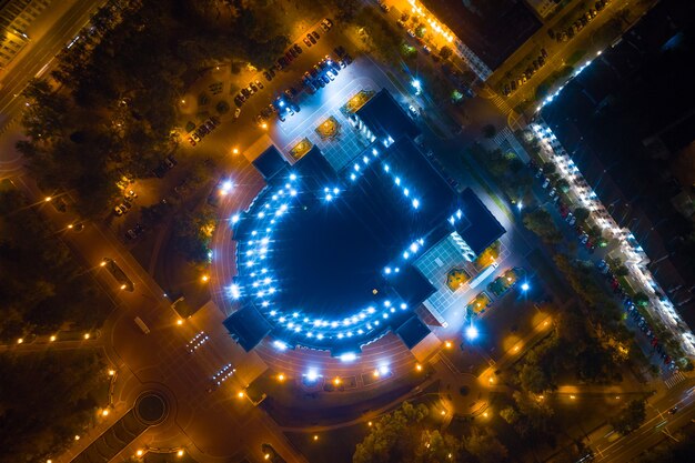 An aerial shot of a large stadium at night, illuminated with bright lights and filled with people. The atmosphere is electric, capturing the excitement of a major event.
