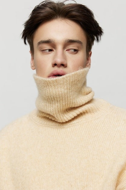 A close-up shot of Lee Jong Suk wearing a light grey turtleneck sweater with subtle cable knit detailing, paired with dark trousers. The focus is on the texture and fit of the sweater, highlighting the cozy and stylish nature of the outfit.